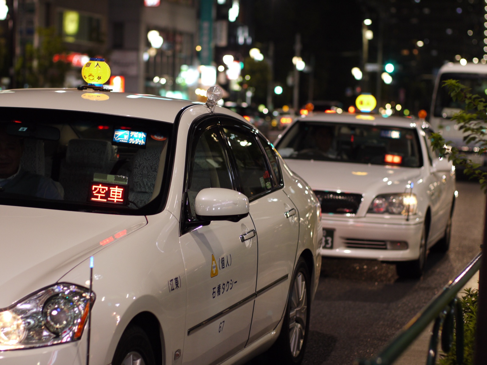 Un taxi de Tokyo au bord du trottoir avec le voyant rouge 空車 (libre) allumé sur le tableau de bord